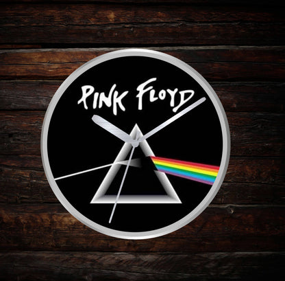 Pink Floyd wall clock with triangle and rainbow design on a dark wooden background
