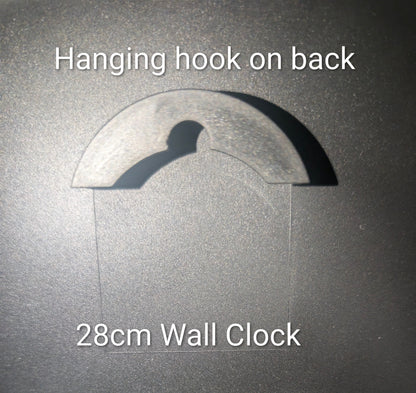 A wall clock shown against a dark textured background with overlaid text reading 'Hanging hook on back' and '28cm Wall Clock', indicating the back of the clock has a hanging hook and the clock diameter is 28 cm.
