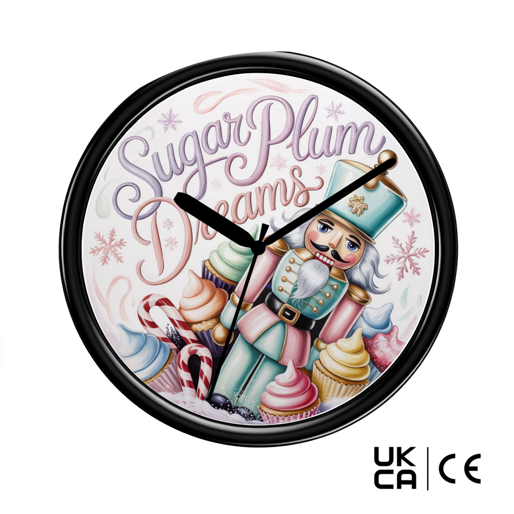 A round wall clock with a black frame and a whimsical nutcracker illustration on a white background. The clock face features the words 'Sugar Plum Dreams' in stylized purple and pink lettering, surrounded by cupcakes, candy canes, snowflakes, and a nutcracker in a teal uniform.