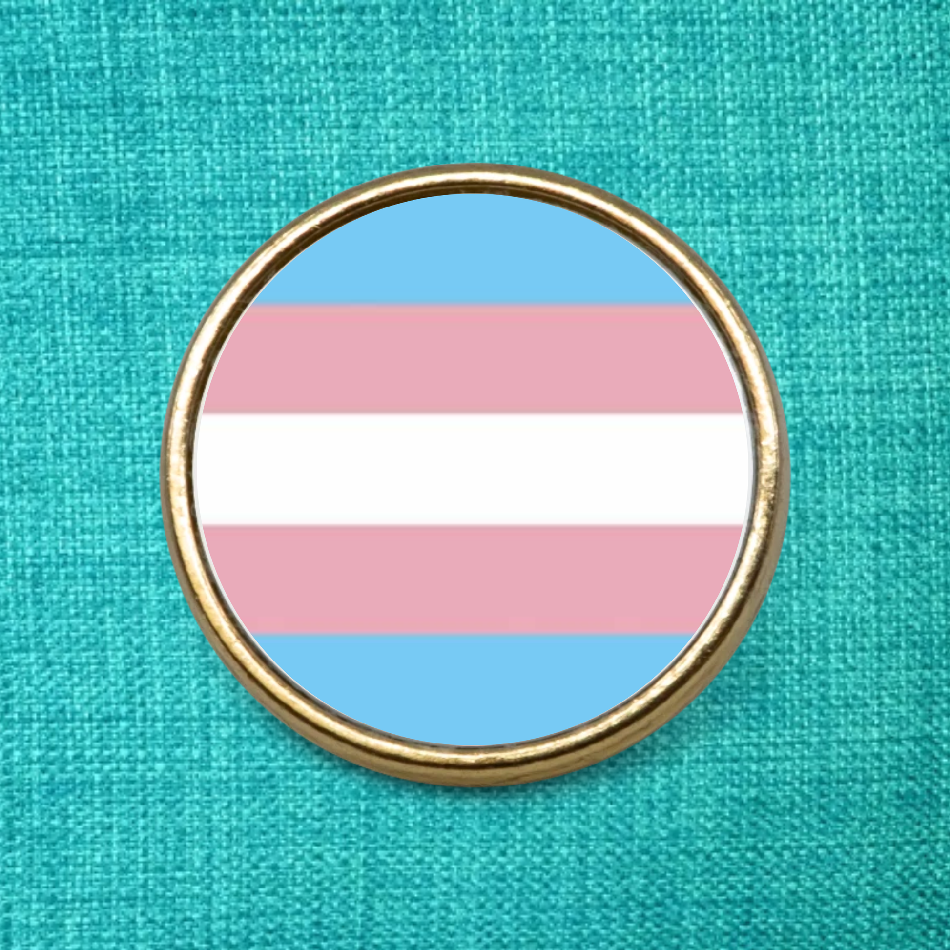 Gold Lapel Badge on a green background featuring the transgender pride flag design