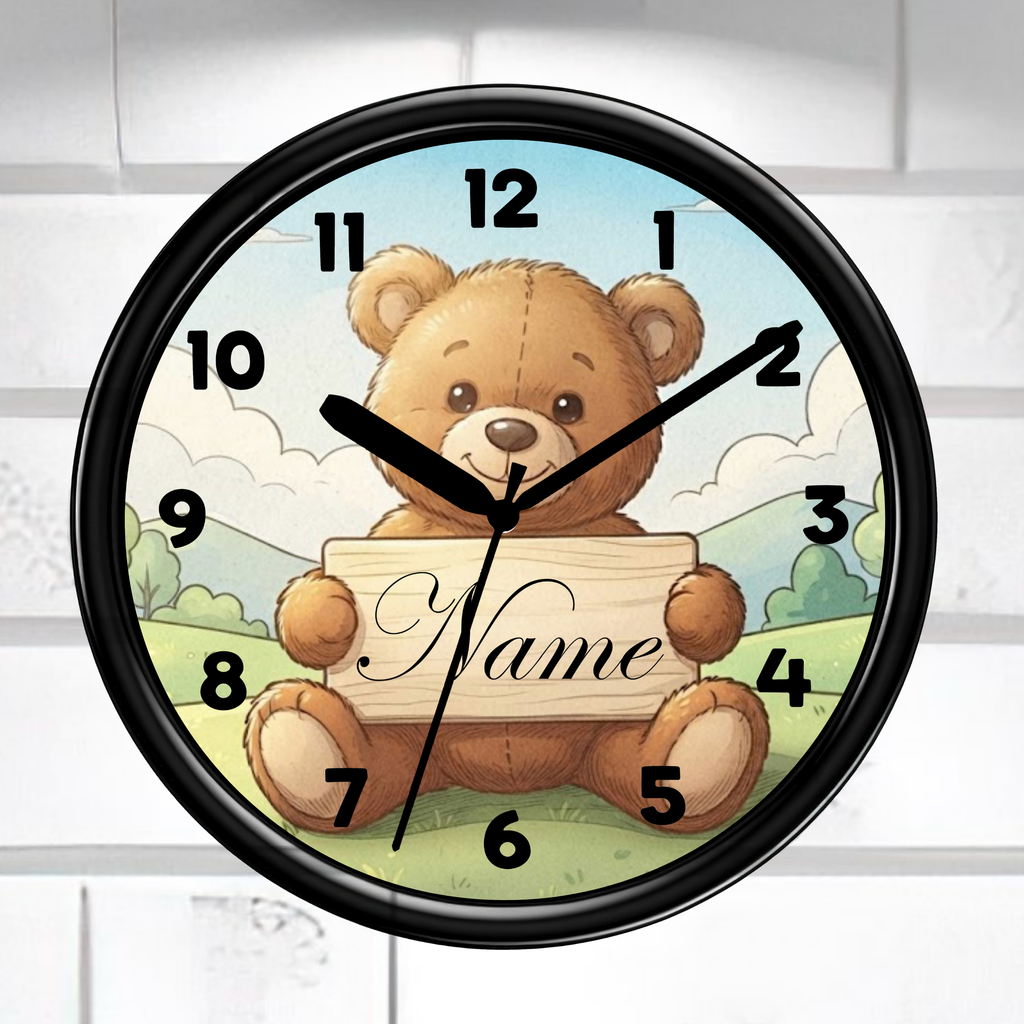A round wall clock with a black frame and a teddy bear illustration holding a sign that says 'Name'. The clock is mounted on a white brick wall.