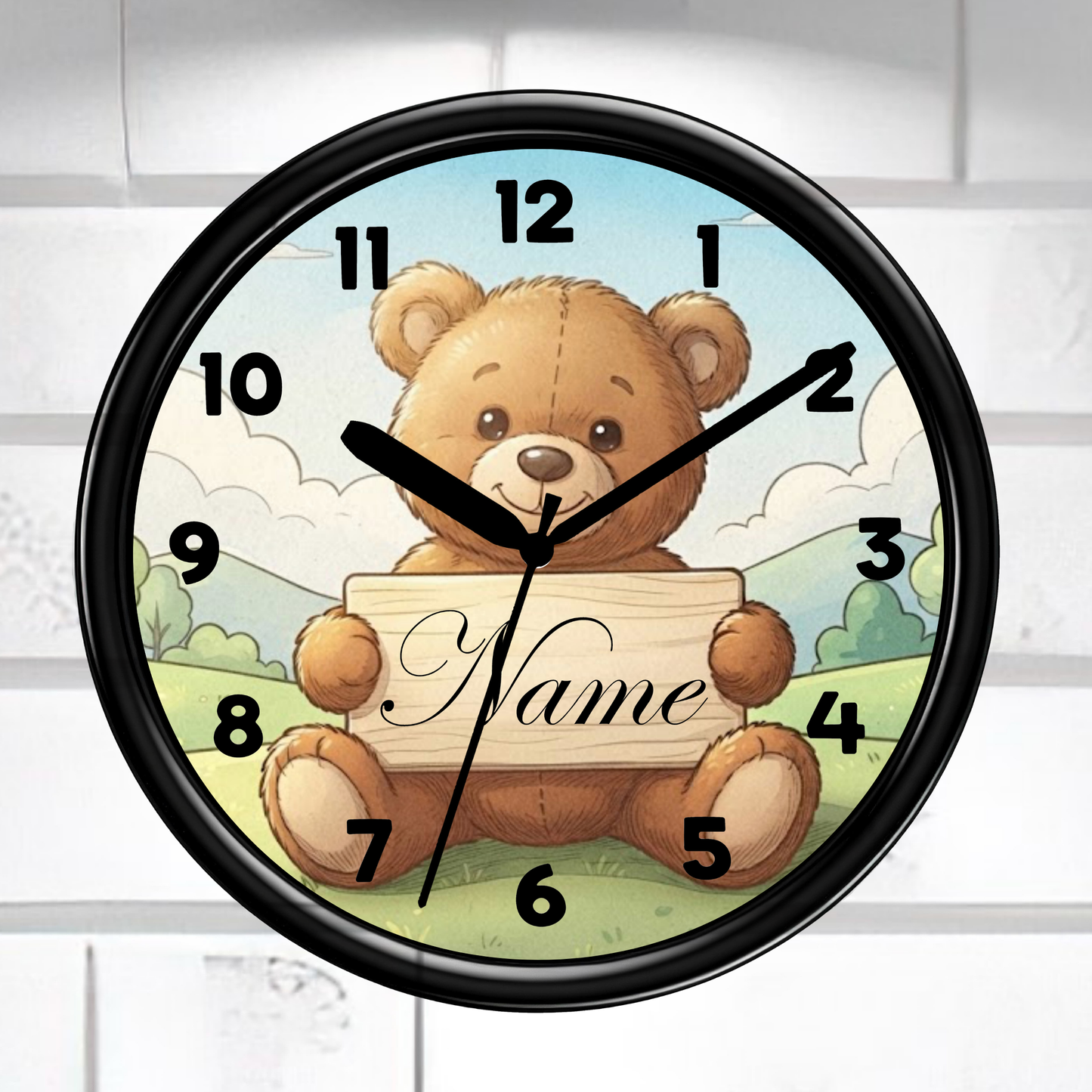 A round wall clock with a black frame and a teddy bear illustration holding a sign that says 'Name'. The clock is mounted on a white brick wall.