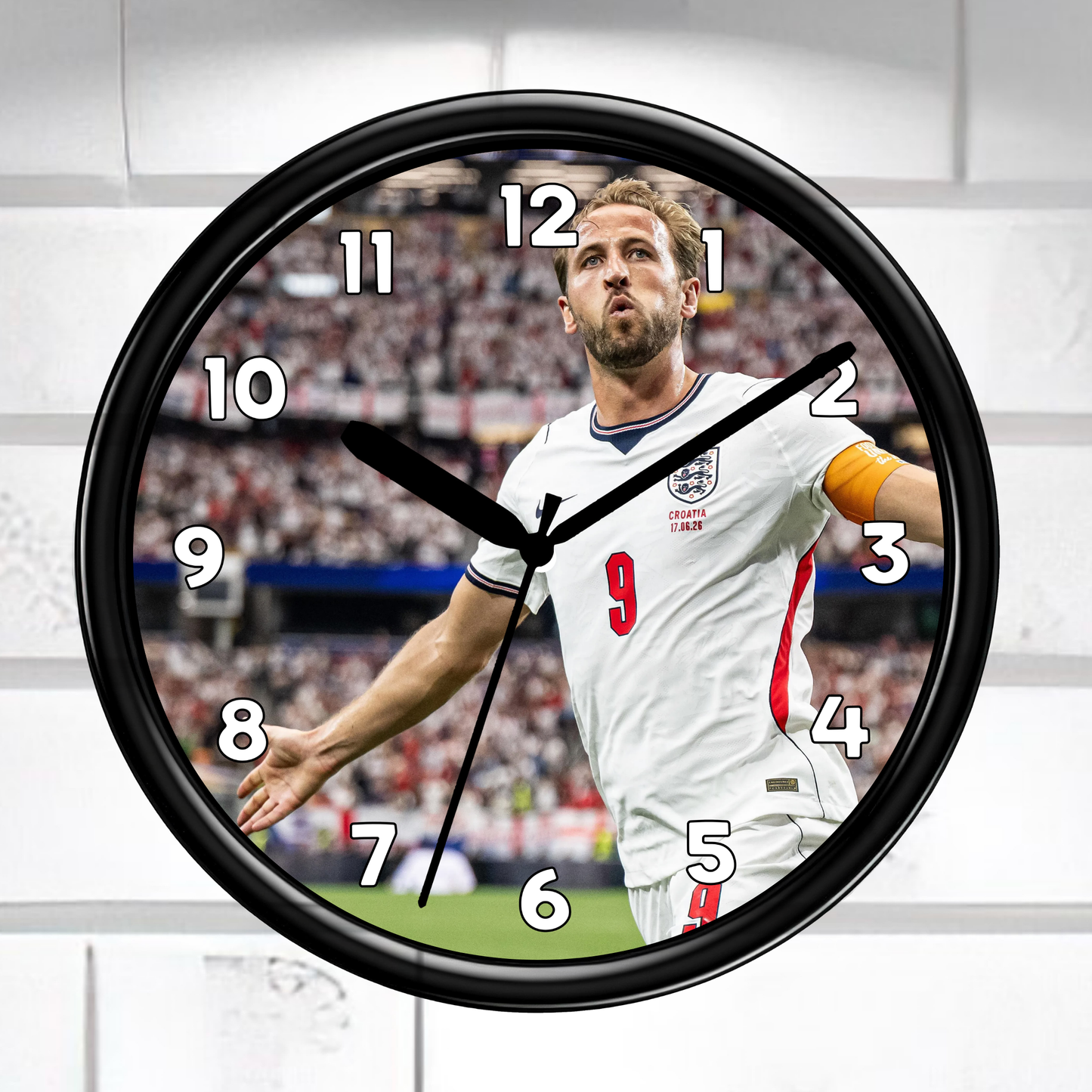 A round wall clock with a black frame and a printed soccer player design on the face, shown against a light gray paneled background.