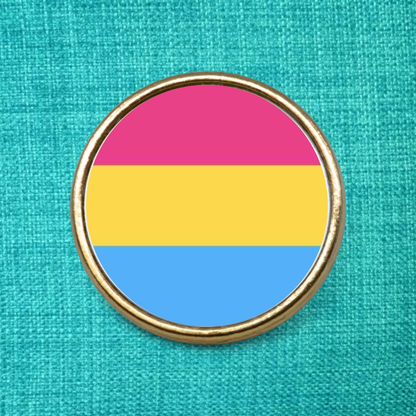 Gold pin badge on a green textured background, featuring the Pansexual flag