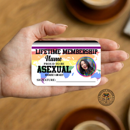 Hand holding a card with 'Lifetme Membership: Proud to be Asexual' design on a wooden surface.