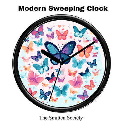 Wall clock with colorful butterfly design and black frame, branded 'The Smitten Society'.