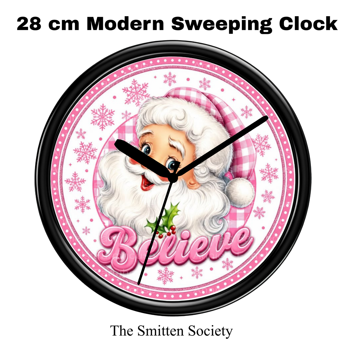 A 28 cm modern wall clock with a black frame and hands, featuring a festive Santa Claus illustration on a pink and white background with snowflakes and the word 'Believe'. Text above reads '28 cm Modern Sweeping Clock' and below reads 'The Smitten Society'.
