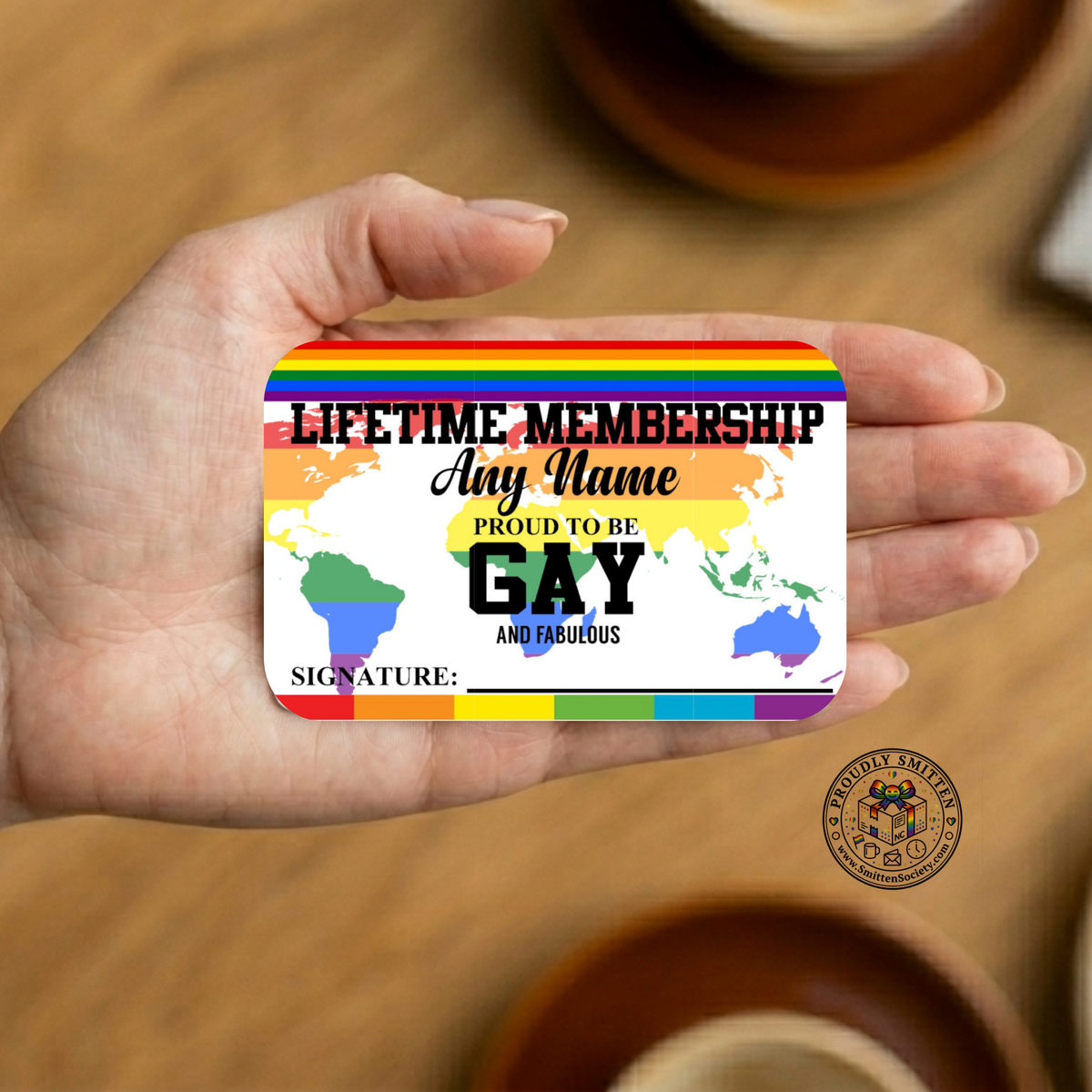 Hand holding a rainbow-themed card with text on a wooden surface