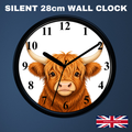 A round wall clock with a black frame and a white face featuring a detailed illustration of a brown highland cow. The clock is shown against a dark blue background with the text 'SILENT 28cm WALL CLOCK' at the top and a small 'Handmade in UK' flag graphic in the bottom right corner.