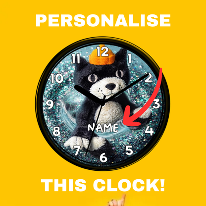A round wall clock with a black cat illustration wearing an orange hat on a glittery blue background, with the words 'PERSONALISE' at the top and 'THIS CLOCK!' at the bottom on a bright yellow background. A red arrow points to the center, and the text 'NAME' appears on the clock face.