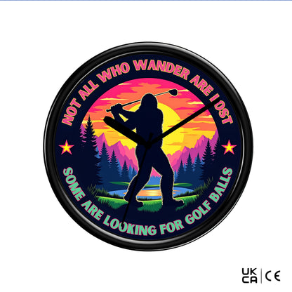 Round wall clock with a silhouette of a person playing golf against a sunset landscape, with text 'Not all who wander are lost. Some are looking for golf balls'.