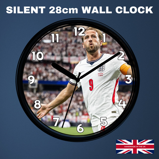 A round wall clock with a black frame and a printed design of football player Harry Kane in a white England jersey. The clock is shown against a dark blue background with the text 'SILENT 28cm WALL CLOCK' at the top and a small 'Made in UK' flag graphic at the bottom right.
