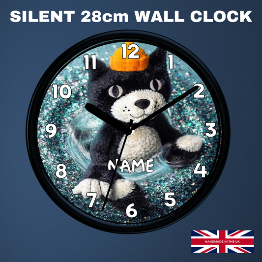 A round wall clock with a black cat plush figure in the center, wearing an orange pumpkin hat, on a glittery blue background. The clock has a black frame and white Arabic numerals.