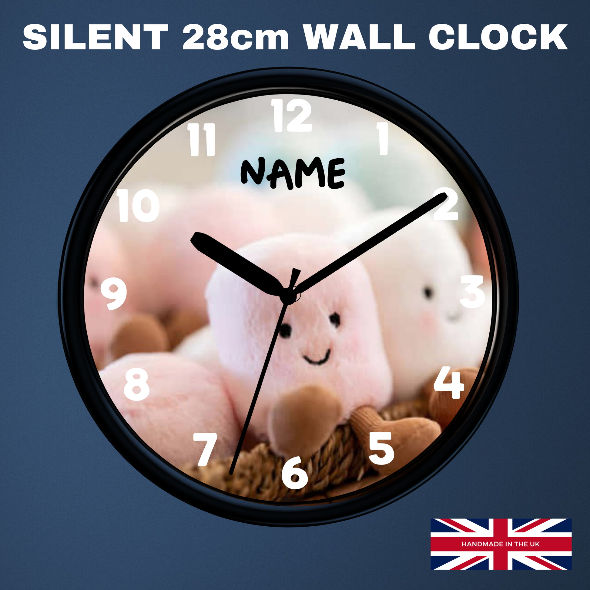 A round wall clock with a black frame and a custom printed face showing a pink plush character. The clock is displayed on a dark blue background with text reading 'SILENT 28cm WALL CLOCK' and a 'HANDMADE IN UK' flag badge.