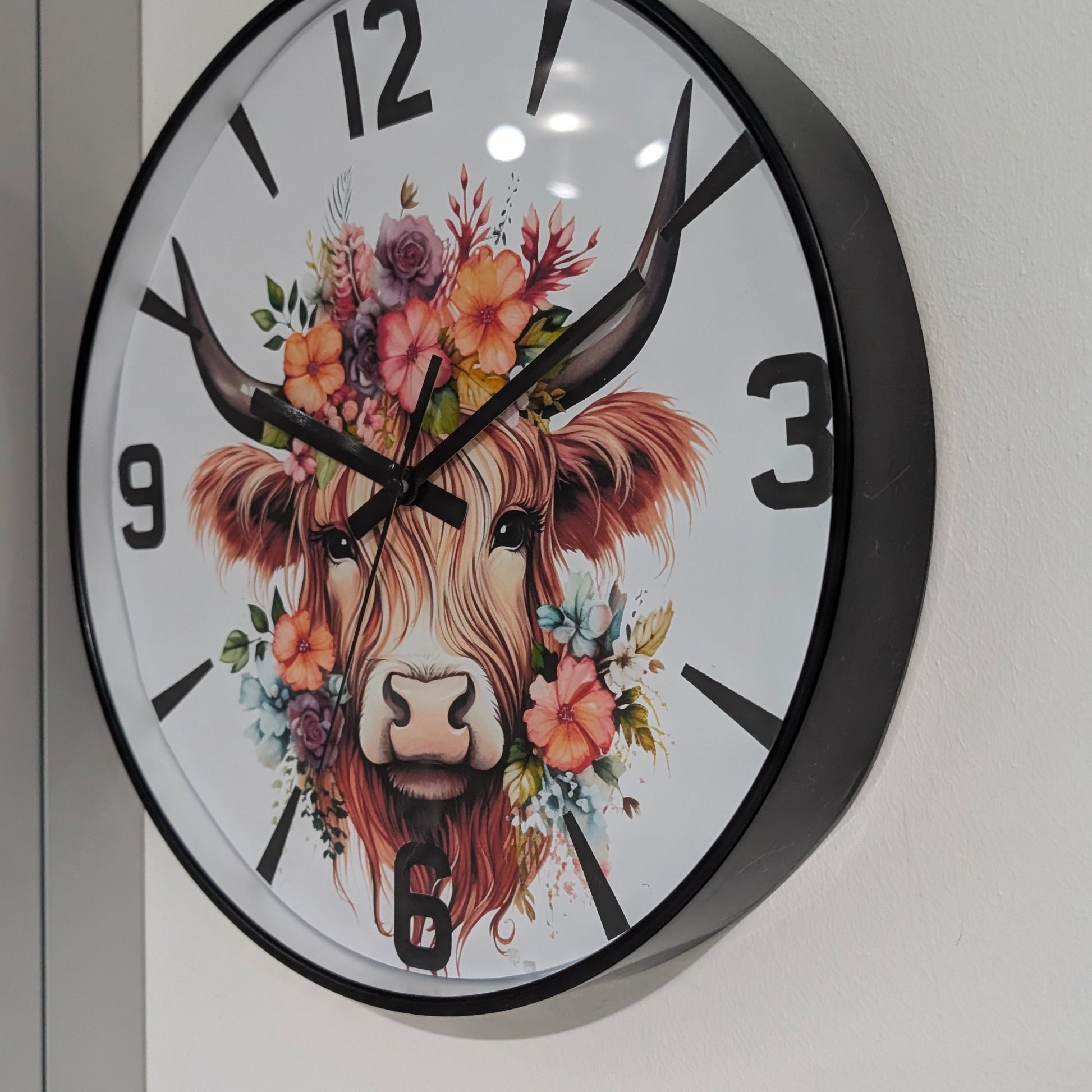Wall clock with a decorative design of a cow's head with flowers on a white background