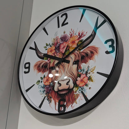 Wall clock with a decorative design of a cow's face surrounded by flowers on a white background.