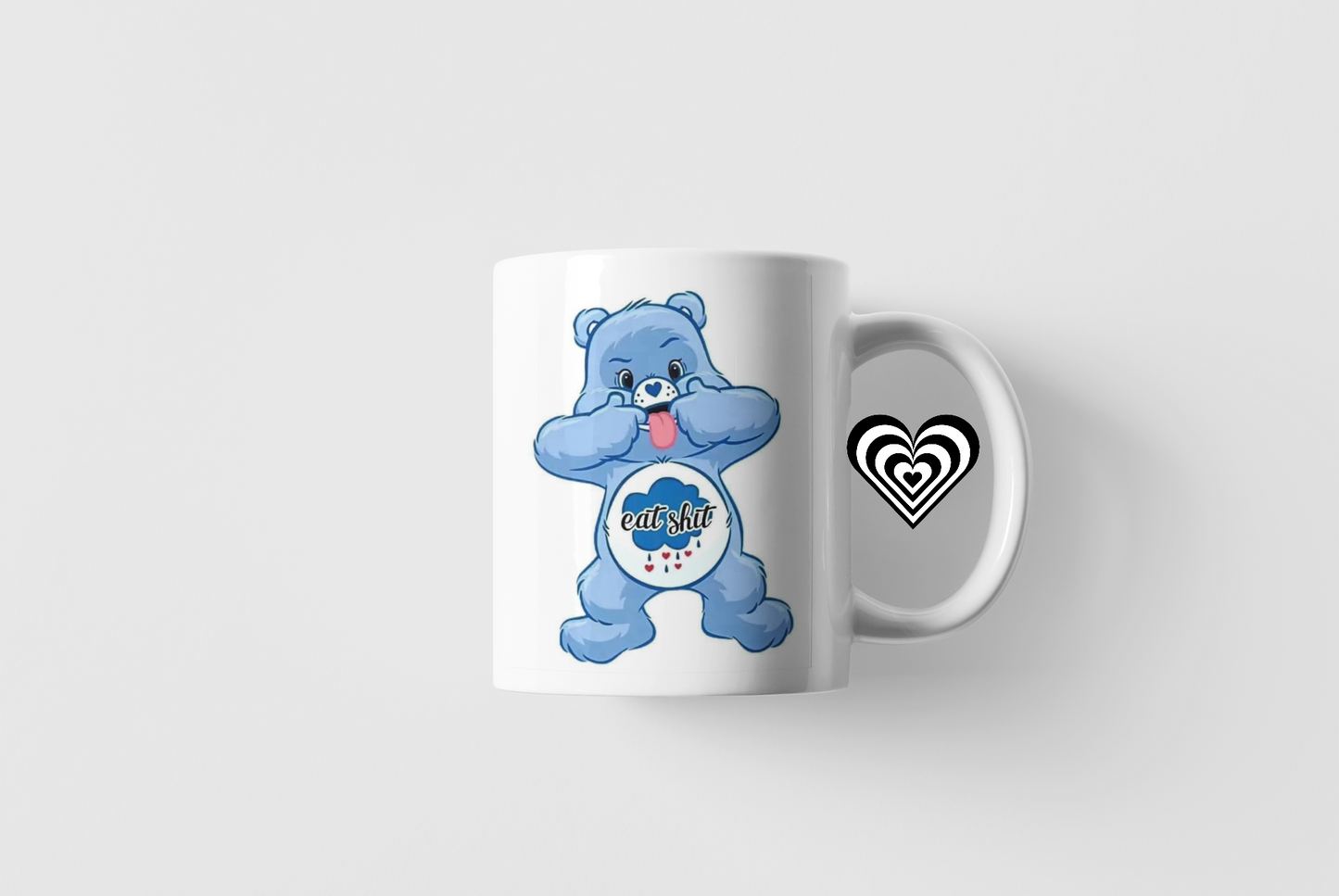 White mug with a blue bear character and a black heart on a white background 'eat sh*t' text