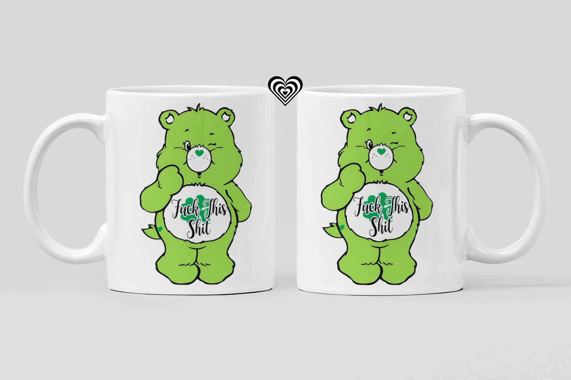 Two white mugs with green cartoon bear characters and 'fu*k this sh*t' text on a light gray background