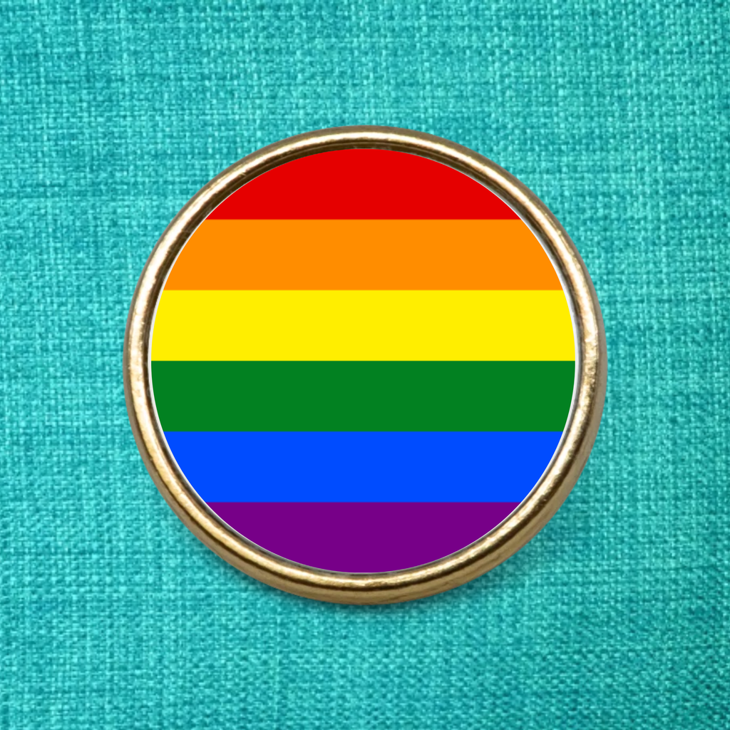Gay Pride Pin Badge, Gold Metal Lapel Badge on a blue material background