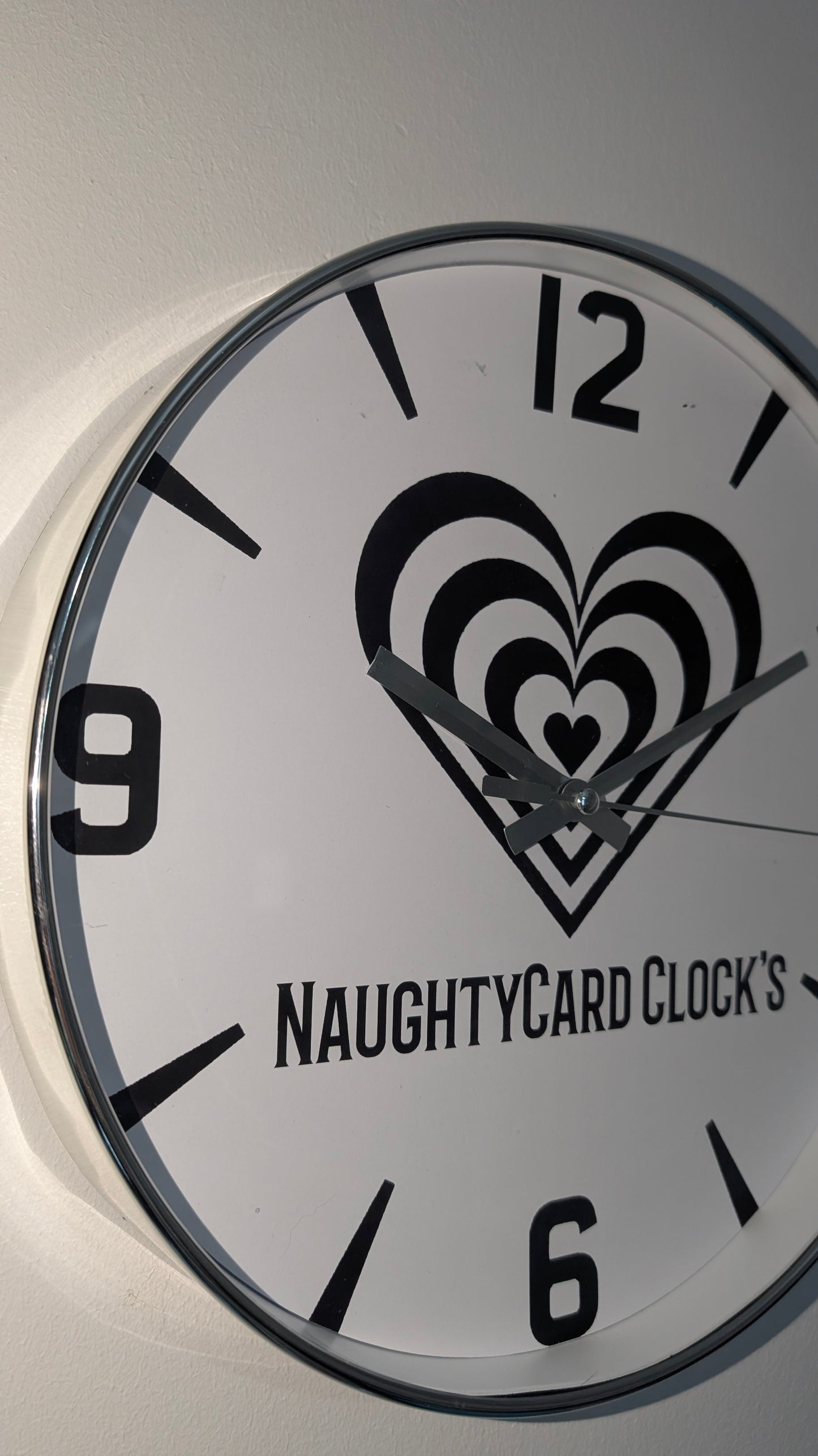 Wall clock with heart design and 'NaughtyCard Clocks' branding on a white background